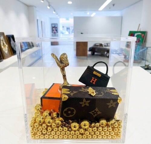 Luxury-Cube-Miniatuur-Kunstwerk-Acrylglas Een handgemaakt miniatuur kunstwerk genaamd Luxury Cube in een heldere acrylglas display 10 cm, met een gouden Spirit of Ecstasy, iconische mini-handtassen en gouden kralen.