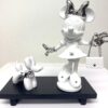 Minnie & Dog Blanc Minnie & Dog Blanc - Pop-art beeld van 20 cm in wit en zilver, met een wit-zilveren Minnie Mouse figuur met Chanel-details en tasje, vergezeld door een kleinere witte balloon dog met parelketting op zwart plateau
