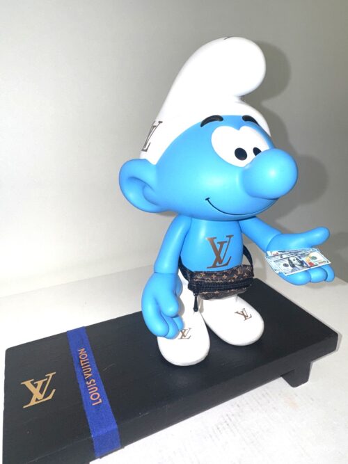 Flex Smurf LV Blauwe smurf sculptuur met Louis Vuitton logo, heuptasje en dollars op een luxe houten plateau, pop-art assemblage kunst.