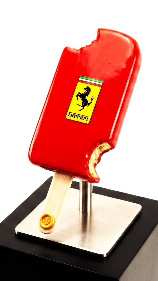 Ferrari Icecream Luxe popart sculptuur van een dieprood Ferrari ijsje met goudkleurige binstenzijde bij de hap, gepresenteerd op een RVS standaard