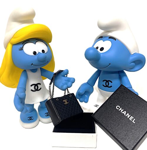 Luxury Present for Smurfin Pop-art kunstwerk Luxury Present for Smurfin door Geov, met Smurfin en een Smurf, een handgemaakt zwart lederen Chanel mini-tasje en een luxe Chanel doosje.